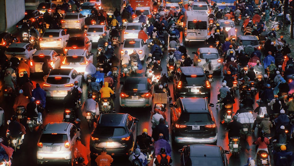 Traffic congestion in Hanoi with cars and motorbikes after rain, showcasing urban hustle.